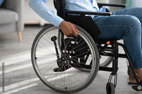 Cropped view of disabled black man sitting in wheelchair at home. Impairment and mobility aids concept