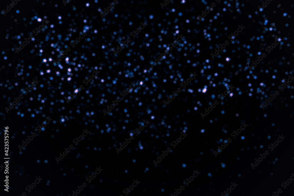 Bright and dark blue little stars blur bokeh on black background. Design element for overlay