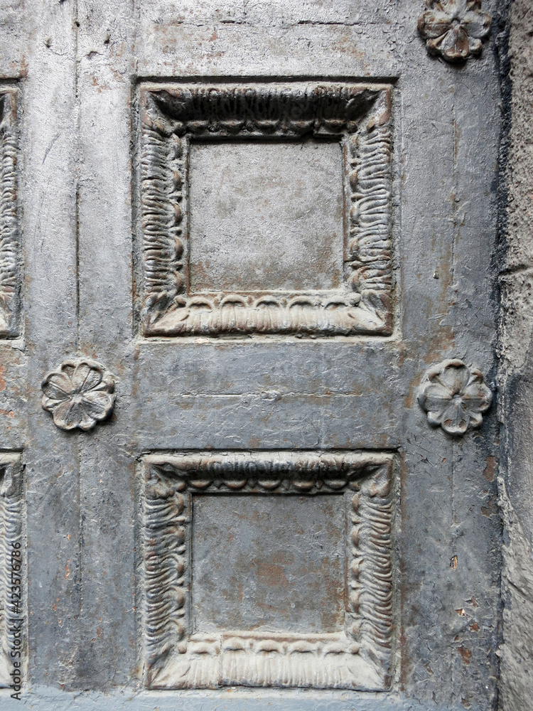 A wooden antique door close up covered in gray paint with a peeling edge