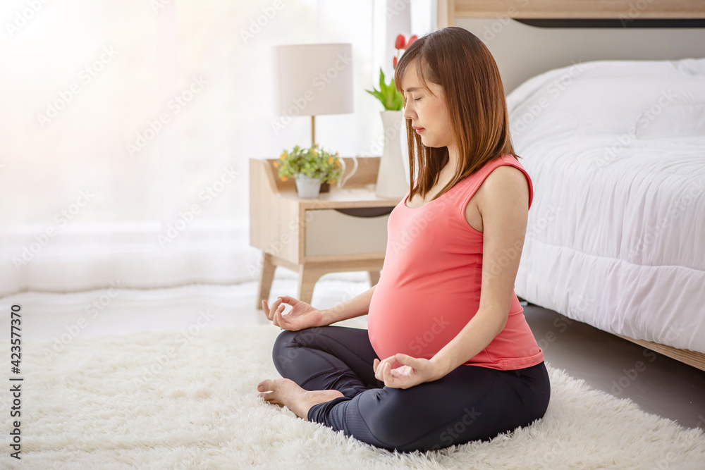 Young Asian pregnant woman exercise in her bedroom in the morning Young Asian pregnant woman exercise in her bedroom in the morning