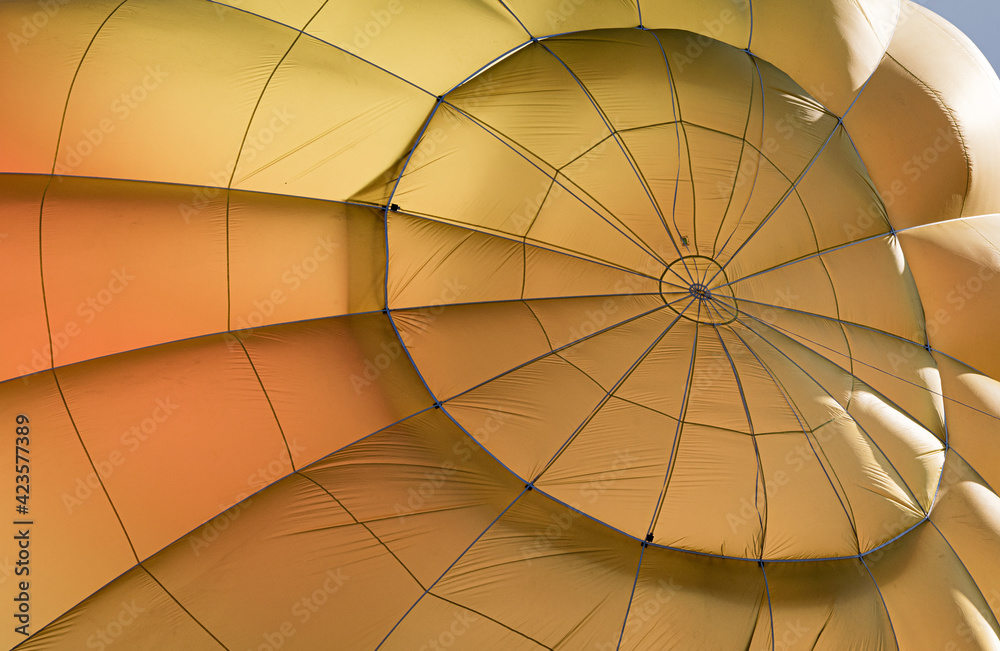 Naklejka premium Der obere Mittelpunkt der Hülle eines gelben Heißluftballons mit den von dort sternförmig verlaufenden Nähten