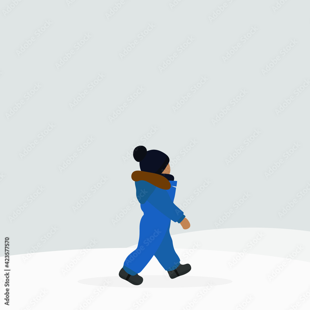 Fototapeta premium A small child in a hat and warm overalls walks in the snow