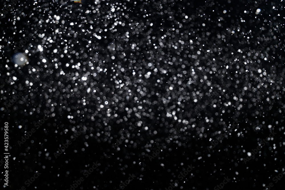 Many snowflakes in blur on black background. Snowfall layer for winter photo