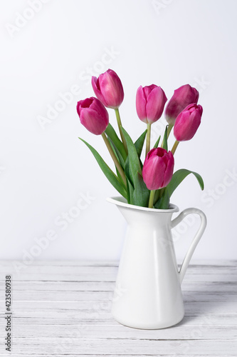 pink tulips in a jug on white background