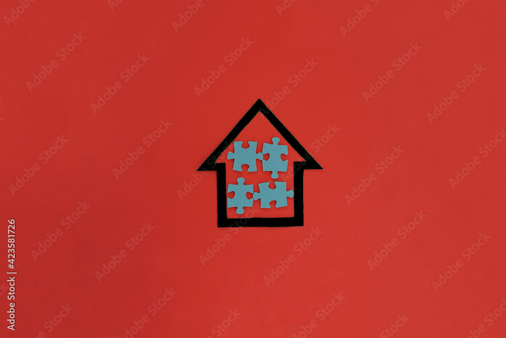 House of black color four puzzles of blue color on a red background. The concept of shared ownership. The real estate market. House of black color four puzzles of blue color on a red background. The concept of shared ownership. The real estate market.