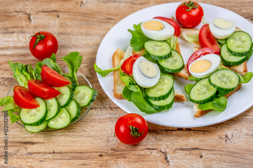 Fried bread toasts with vegetable and egg slices and salad