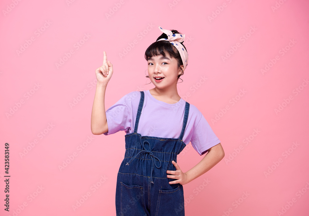 smiling Asian girl pointing finger on blank space beside in pink isolated background smiling Asian girl pointing finger on blank space beside in pink isolated background