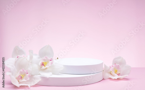 White geometric shapes podium for product display on pink background with orchid flowers and palm leaves. stand for product promotion in minimal style. Copy space for your design. Banner. 