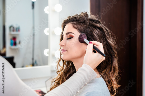 Make up artist applying professional make up to beautiful young woman.