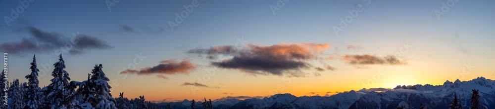 Obraz premium Panoramic View of Canadian Nature Landscape on top of snow covered mountain and trees during colorful spring sunset. Taken on a hike up Elfin Lake in Squamish, North of Vancouver, BC, Canada.