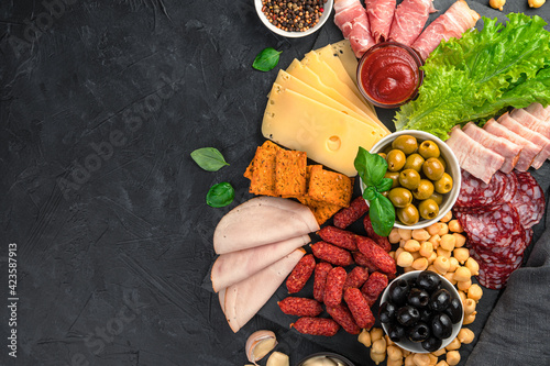 Принти на полотні Different types of sausage and cheese with olives and salad on a black background