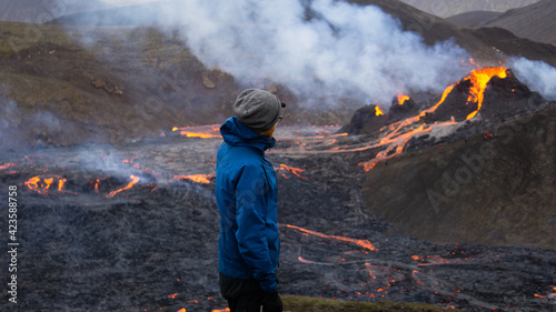 A hiker watches a small volcanic eruption in Mt Fagradalsfjall, Southwest Iceland. A small eruption occurred in the area in March 2021, only about 30 km away from the capital of Reykjavik.