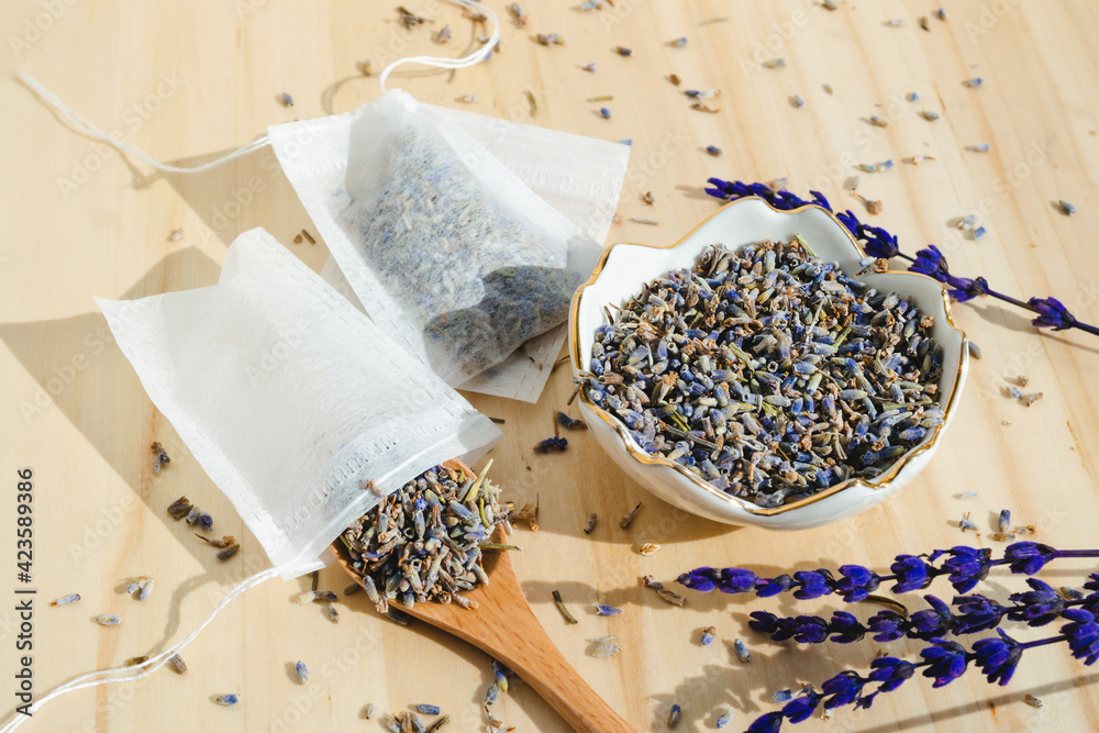 Dried lavender, spoon and tea bag sachet on wooden table. Organic flower herbal drink. Zero waste wrapper. Dried lavender, spoon and tea bag sachet on wooden table. Organic flower herbal drink. Zero waste wrapper.