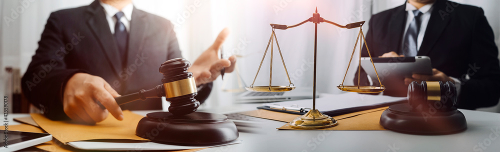 Justice and law concept.Male judge in a courtroom with the gavel, working with, computer and docking keyboard, eyeglasses, on table in morning light Justice and law concept.Male judge in a courtroom with the gavel, working with, computer and docking keyboard, eyeglasses, on table in morning light