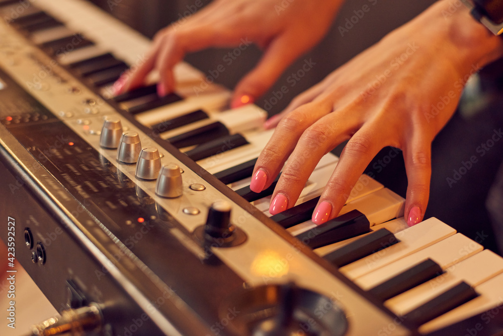 Close-up of musician playing on keyboard of electric piano in studio