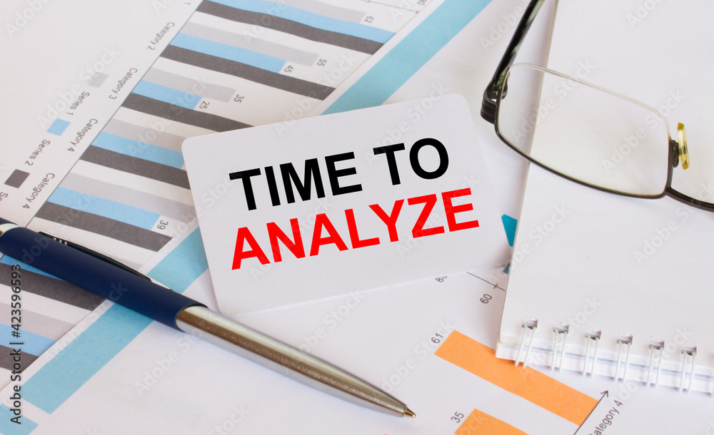 Business card with text Time To Analyze lies on financial charts with pen and eyeglass Business card with text Time To Analyze lies on financial charts with pen and eyeglass