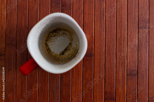Red cup of coffee with coffee grounds on wooden background