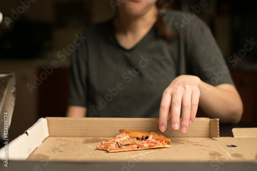 Woman takes a bite of the pizza and puts it in the box. Overeating and satiety