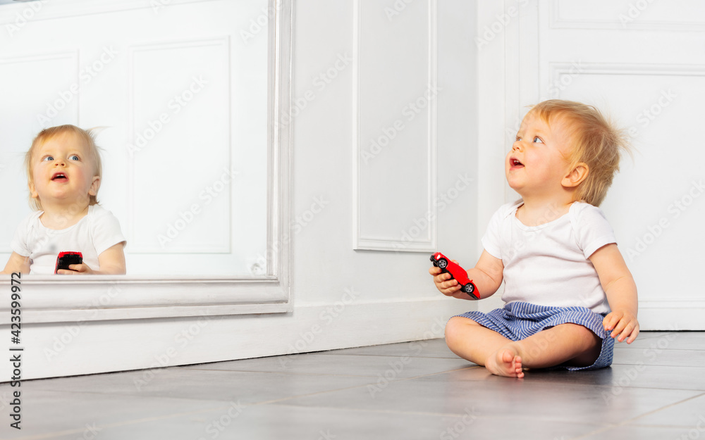 Happy toddler boy play with toy car near mirror Happy toddler boy play with toy car near mirror