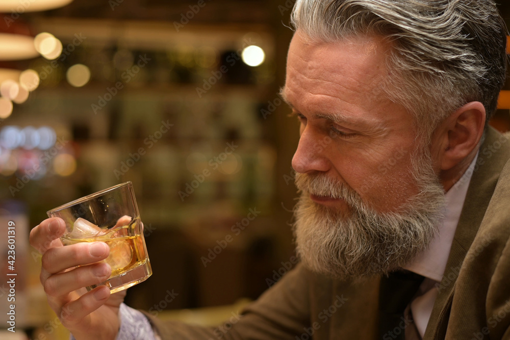 man looks at the whiskey glass in his hand. Adult man drinking in a restaurant man looks at the whiskey glass in his hand. Adult man drinking in a restaurant