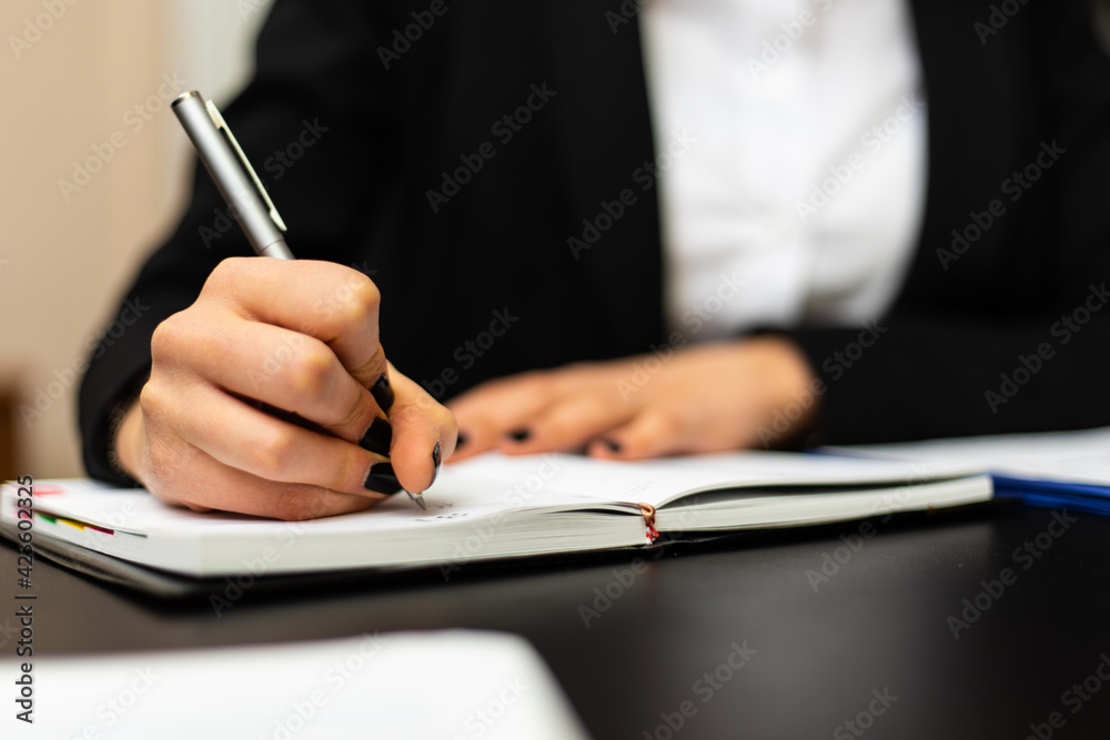 Closeup of a female manager writing and taking notes on a sheet in her office Closeup of a female manager writing and taking notes on a sheet in her office