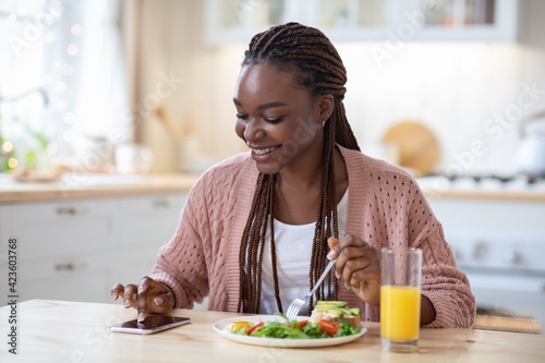 Callories Counting App. Black woman using smartphone while having breakfast in kitchen