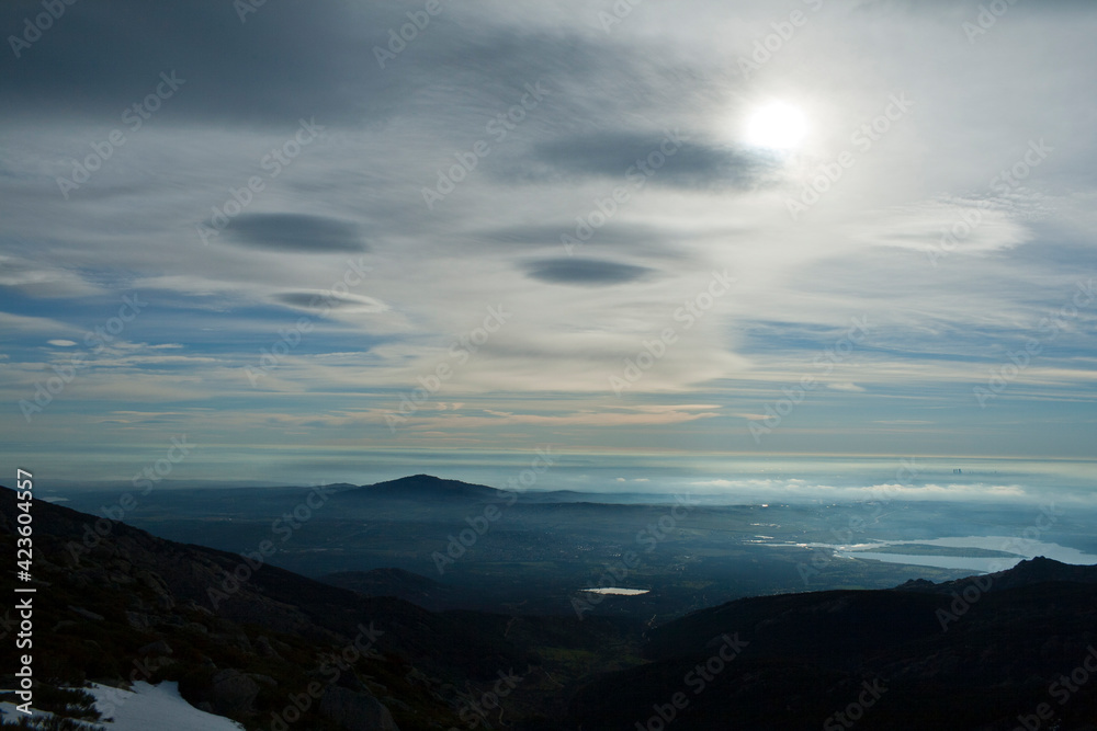 plain with haze, cirrus clouds and lenticular clouds seen from the top of a mountain