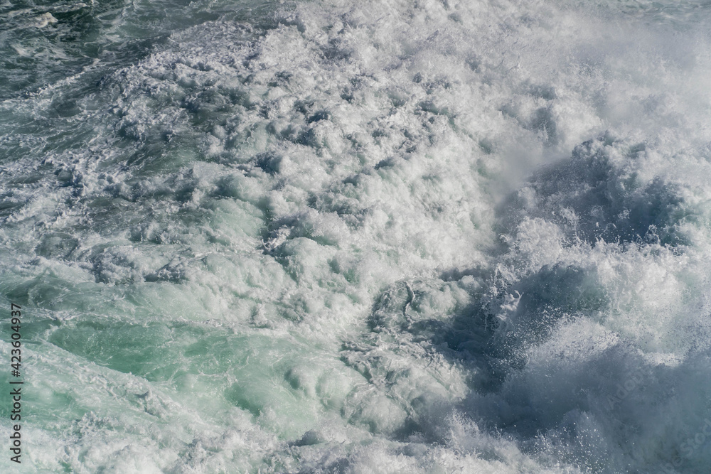 Seawater from a wave as it breaks against a rock, sea foam Seawater from a wave as it breaks against a rock, sea foam