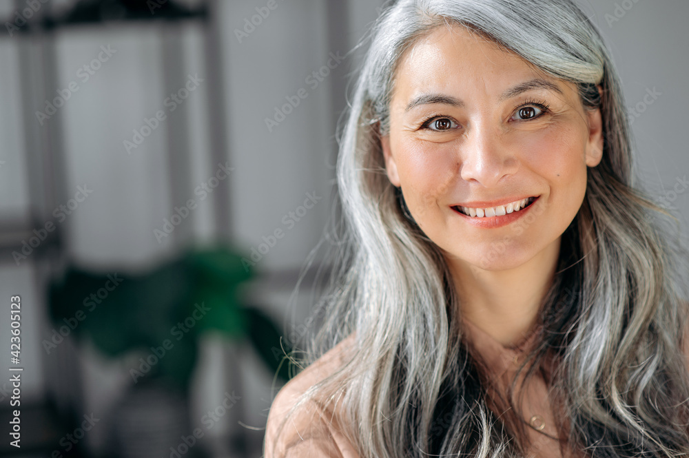 Close-up portrait of happy successful influential senior gray-haired Asian business woman, top manager, lawyer, real estate agent, standing at office, in stylish wear, looks at camera, smiles friendly Close-up portrait of happy successful influential senior gray-haired Asian business woman, top manager, lawyer, real estate agent, standing at office, in stylish wear, looks at camera, smiles friendly