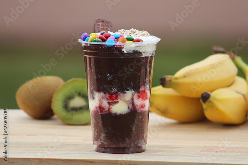Açaí cup with strawberry, banana, kiwi and sweets on a wooden table
