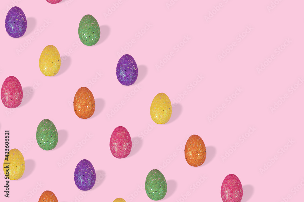 Creative Easter pattern made of colorful eggs arranged on pastel pink background with space for text.