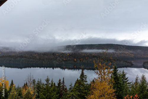 Vue d'une rive d'un lac calme avec nuages très bas en automne 