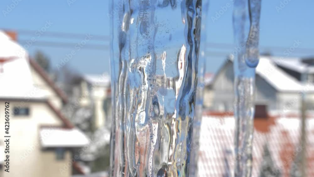 Icicles Melting on Sunny Spring Day Close-Up with Houses in Background Icicles Melting on Sunny Spring Day Close-Up with Houses in Background