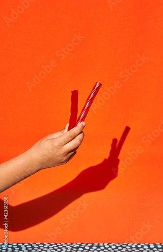 Conceptual vertical photo of a child's hand with two liquorices on orange background photo