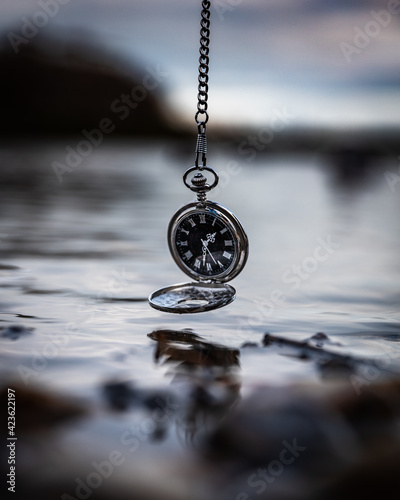 pocket watch hanging above a lake photography