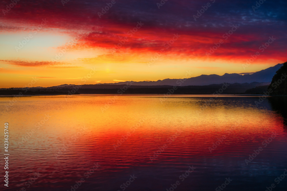 Amazing red and yellow sky colour reflected in Okarito Lagoon with a backdrop of the Southern Alps at Dawn