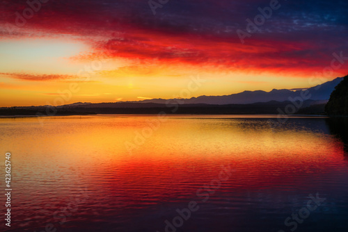 Amazing red and yellow sky colour reflected in Okarito Lagoon with a backdrop of the Southern Alps at Dawn