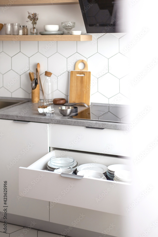 Comfortable white gray kitchen interior open box full of various crockery porcelain or glass plates Comfortable white gray kitchen interior open box full of various crockery porcelain or glass plates