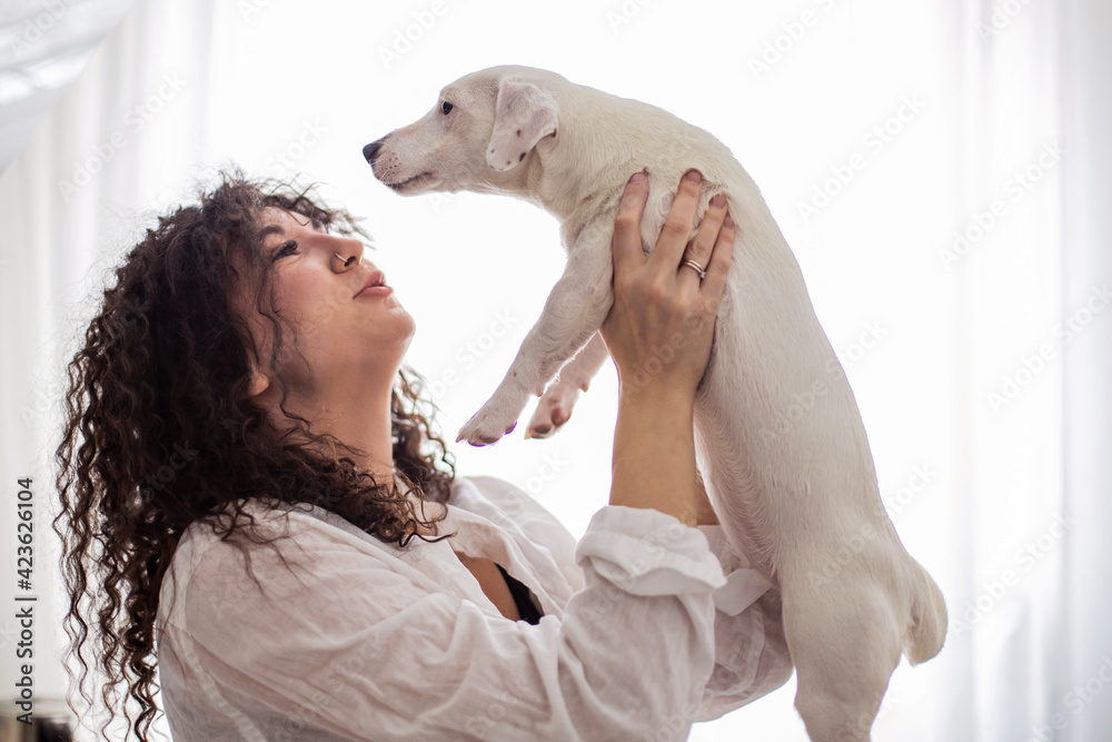 Happy curly brunette woman pet owner holding dog Jack Russell Terrier breed feeling love friendship Happy curly brunette woman pet owner holding dog Jack Russell Terrier breed feeling love friendship