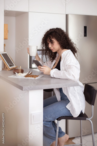 Joyful brunette woman chatting surfing internet use smartphone enjoying coffee break at cafe