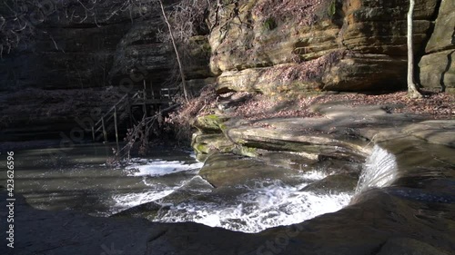 Forest river cascading down small rocky steps in rocky valley photo