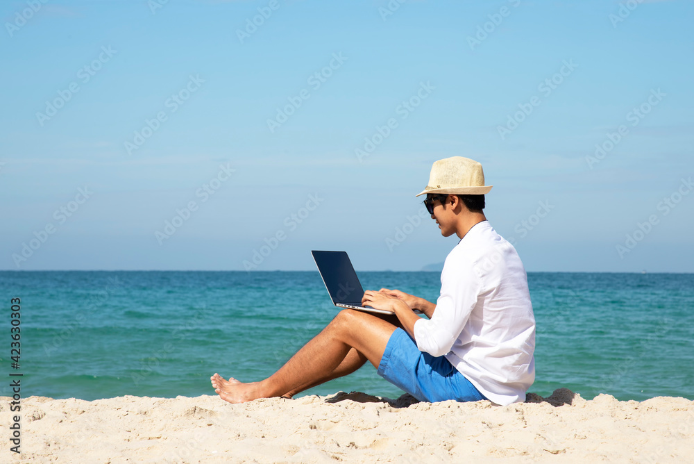 Lifestyle freelance man using laptop working and relax on the beach.  Asia people success and together your work pastime and meeting conference on internet in holiday. Business and Summer Concept