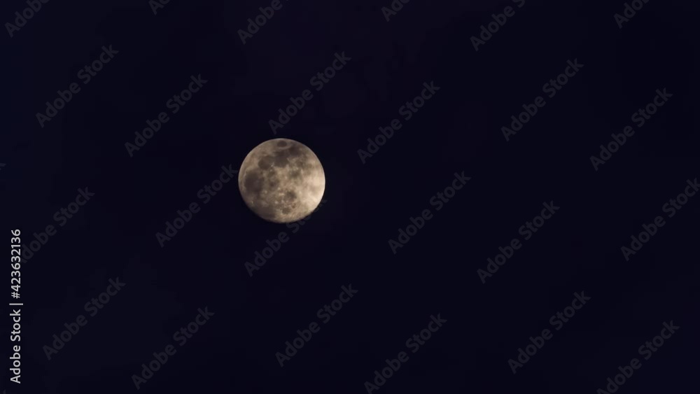 Time-lapse shot of white clouds passing by the moon on a black sky Time-lapse shot of white clouds passing by the moon on a black sky