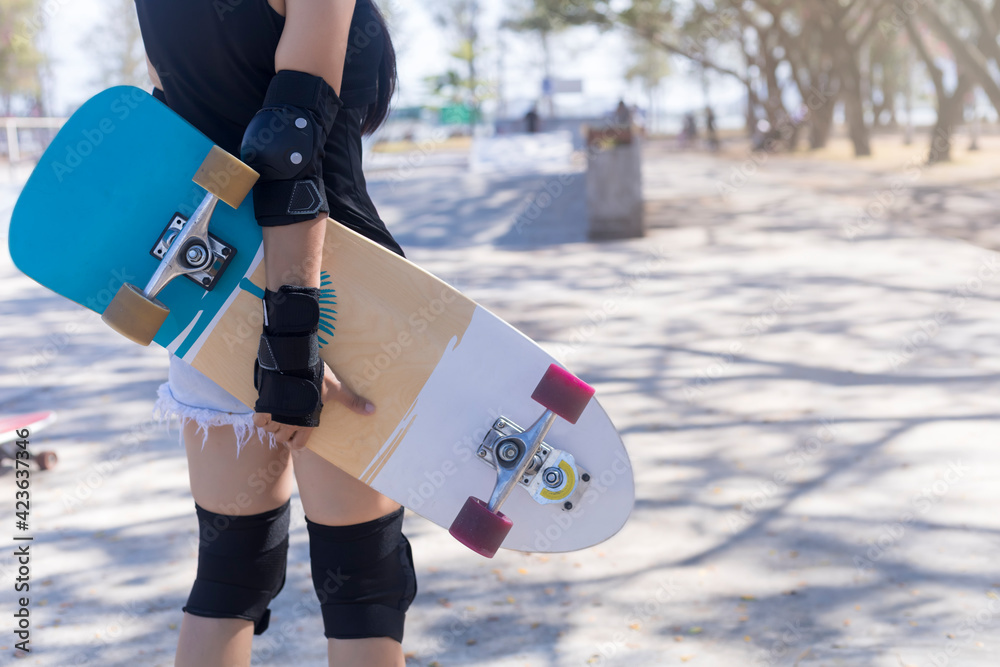 Close up on young women wear protection and hand hold skateboard, surf skate  on public skate ramp park background. Free relax skateboard surf skate  trendy concept. Photos | Adobe Stock