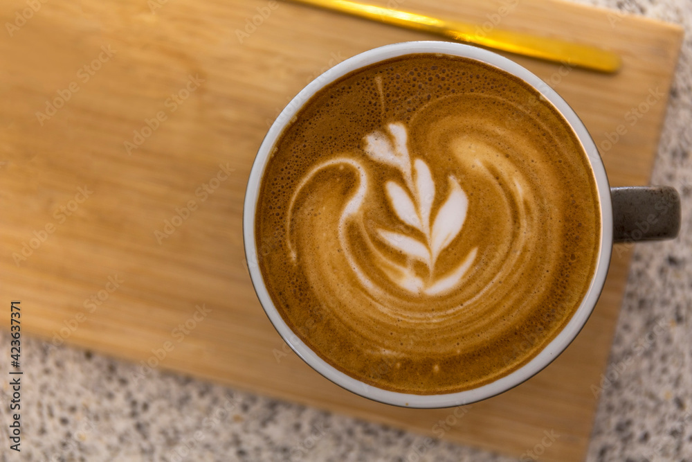Soft focus Top view close up of hot espresso, latte coffee in a red ceramic cup on blur wood table background.