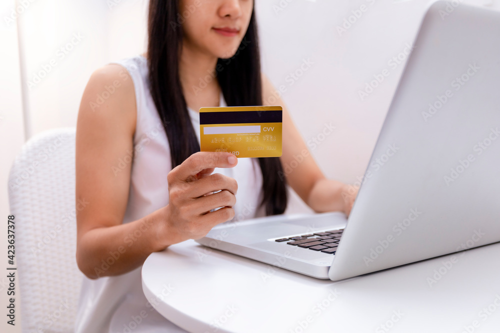 Young woman holding credit card and using laptop computer. Women working at home. Online shopping, e-commerce, internet banking, spending money, working from home concept. Technology shopping online Young woman holding credit card and using laptop computer. Women working at home. Online shopping, e-commerce, internet banking, spending money, working from home concept. Technology shopping online