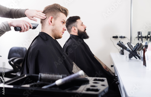 Men having their hair cut by hairdressers at hair salon