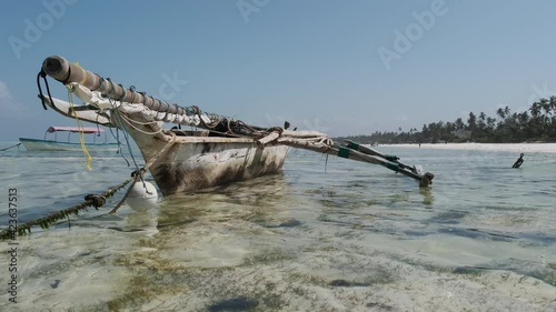 Traditional African fishing boat stranded in the sand on the beach at low tide, Zanzibar. Old dry, wooden rowboat sitting on a sandbank by Ocean near coast. Exotic shore of Matemwe, Tanzania. Africa photo