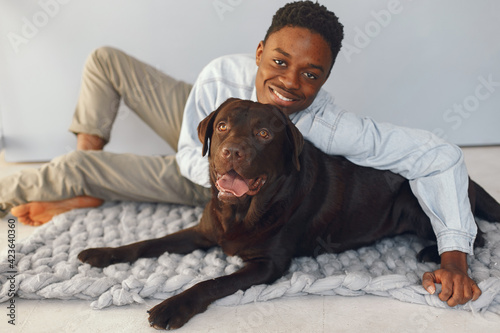 Handsome black man sitting on a blue background with a dog photo