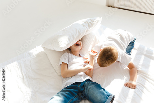 Indoor positive activity. Small children jumping on a bed and having fun in sunshine